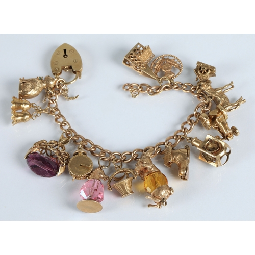 83 - 9ct gold charm bracelet with fourteen assorted gold charms to include cat, bells, clock, tractor, et... 