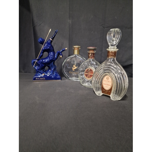 184 - Four REMY MARTIN champagne Coganc bottles. Three clear glass and one Blue Limgoes porceline Centaur ... 