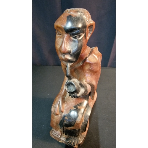 29 - A hand carved African man smoking a pipe.  In African Hardwood Approximately 30cm H