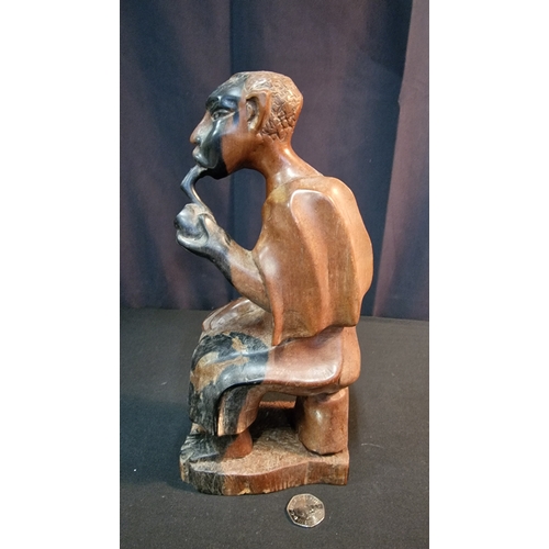 29 - A hand carved African man smoking a pipe.  In African Hardwood Approximately 30cm H