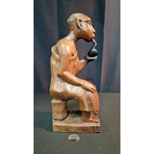 29 - A hand carved African man smoking a pipe.  In African Hardwood Approximately 30cm H