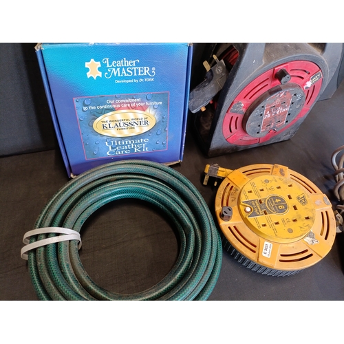 299 - Selection of power extension leads, a hosepipe and a leather care kit