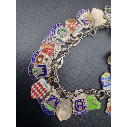 215 - A sterling silver bracelet with a large quantity of sterling silver charms from various locations.