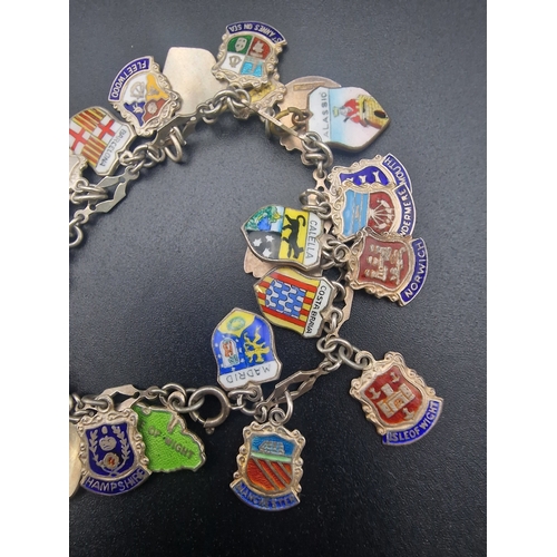 215 - A sterling silver bracelet with a large quantity of sterling silver charms from various locations.