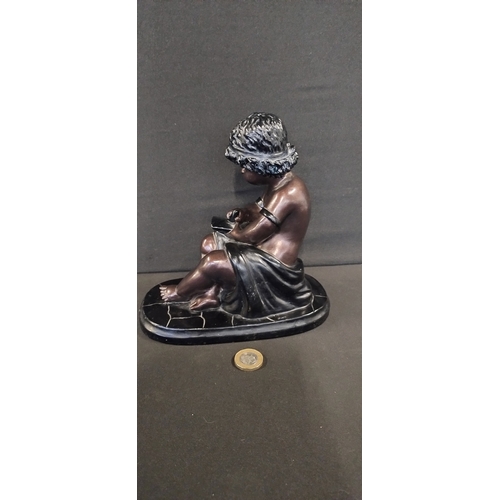 83 - Bronze and black Resin Figure of a child seated with a book. Measures approx H 17.5 x W 18.5 x D 11 ... 