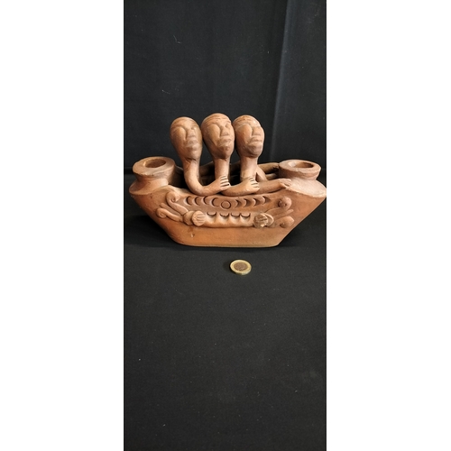 276 - Terracotta candle holder depicting 3 African figures, seated in a decorated boat