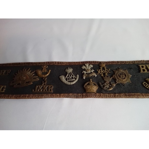 37 - Military belt with cap & collar badges attached. 27 badges in total