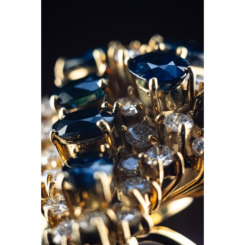 63 - Stunning cocktail ring set in 18ct gold featuring a nest of 8 6.5mm by 4.5mm sapphires surrounded by... 