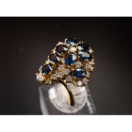 63 - Stunning cocktail ring set in 18ct gold featuring a nest of 8 6.5mm by 4.5mm sapphires surrounded by... 