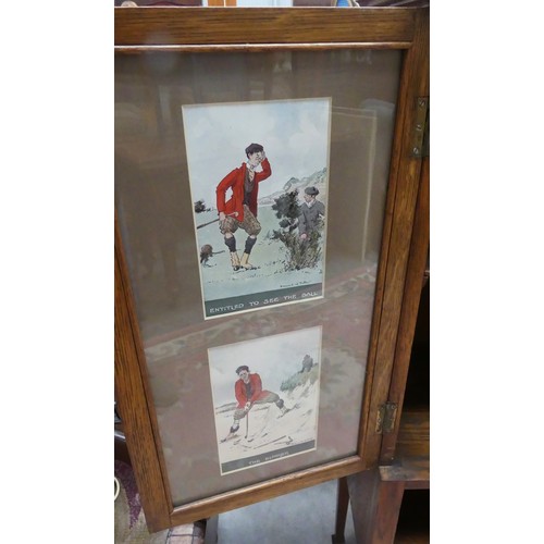 2293 - Edwardian Two Door Oak Cabinet - the door interiors mounted with Golfing prints by Edward G Fuller.