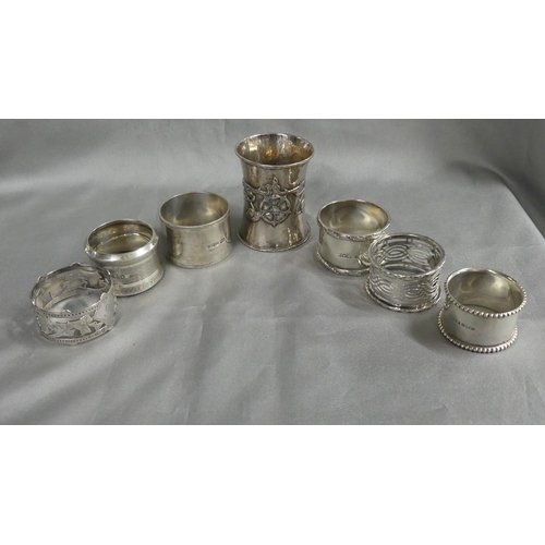 2231 - Six Individual Silver Napkin Rings and one large Arts & Crafts Rose Decorated Ring, 7.8oz troy.