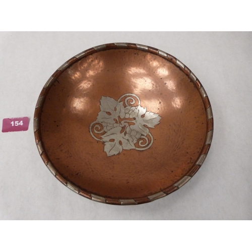 154 - A Hugh Wallace planished copper and silvered bowl, the centre with vine fruits. Impressed monogram. ... 