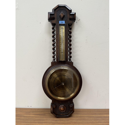 219 - An oak aneroid wall barometer with brass dial and temperature register. 31' high