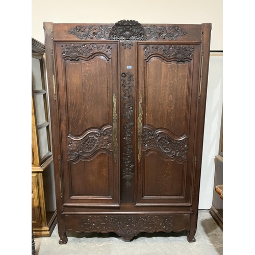 356 - A 19th century French joined oak armoire, carved with trailing foliage, enclosed by a pair of fielde... 