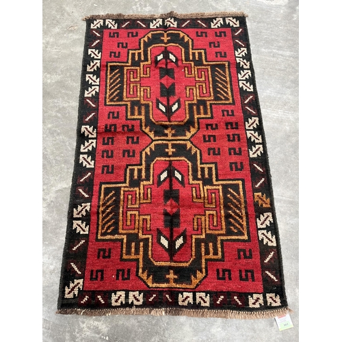 382 - A Balochi red ground rug. 1.41m x 0.86m