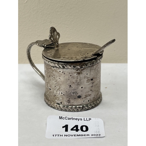 140 - An Edward VII silver mustard pot with blue glass liner and silver spoon. Chester 1909. Marks rubbed.... 