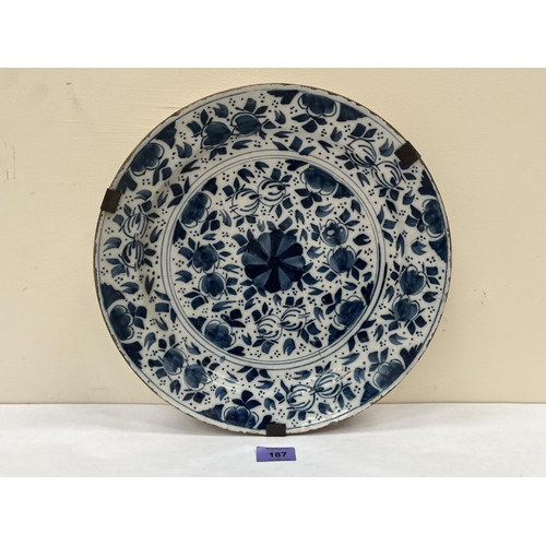 187 - An 18th century tin glazed blue and white charger. 13¾' diam. Extensive repairs