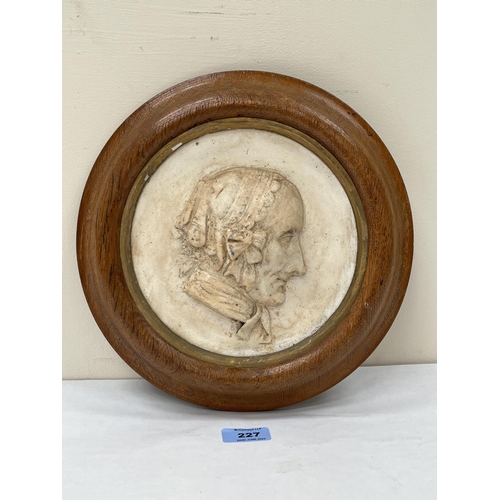 227 - A 19th century plaster relief plaque depicting a lady's head in profile. The oak frame. 11¼' diam.