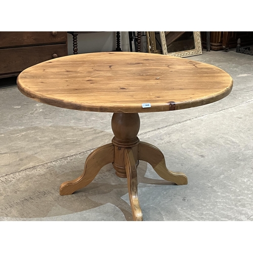 388 - A pine table, the round top on quadripartite support. 47' diam