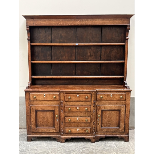 390 - A George III joined oak dresser, North Wales, the raised rack with three shelves, the breakfronted b... 