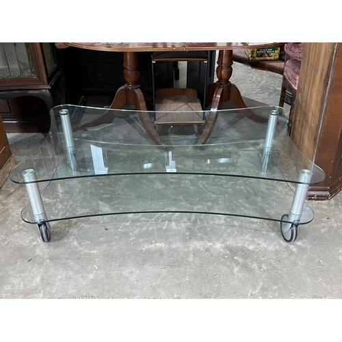 565 - A modernist design two tier glass low table on castors. 52