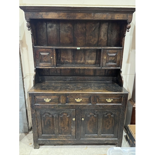 579 - An early 18th century joined oak canopy top dresser, the base with three drawers over a pair of two ... 