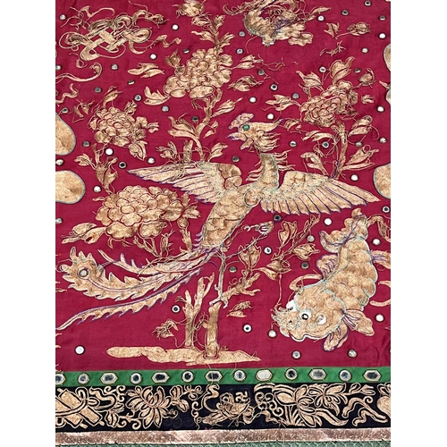 194 - A Chinese polychrome silk hanging worked with gilt and other coloured threads and mirrored appliques... 