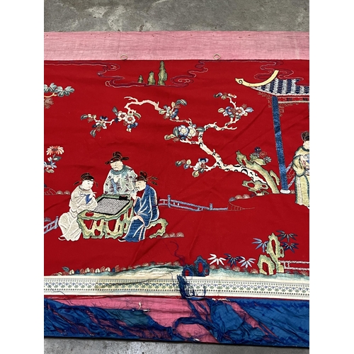 195 - A Chinese polychrome silk hanging worked in coloured threads with figure groups, buildings, trees an... 