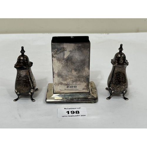 198 - A silver matchbox stand, base weighted, and a pair of silver pepperettes.