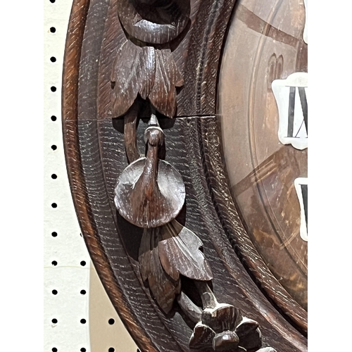 102 - A late 19th Century Black Forest type oak wall clock with two train spring barrel movement striking ... 