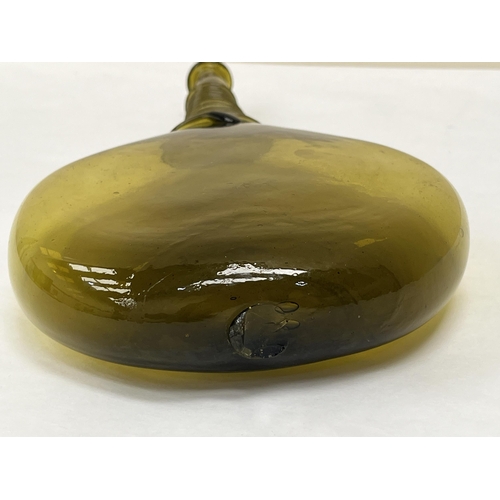 128 - A 17th Century Persian glass saddle flask of amber green colour and typically flattened ovoid form w... 