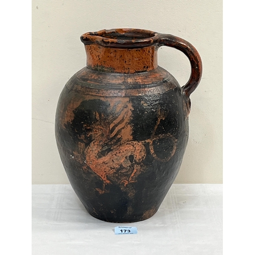 173 - An antique glazed terracotta earthenware jug decorated in red slip with a dragon. 12½