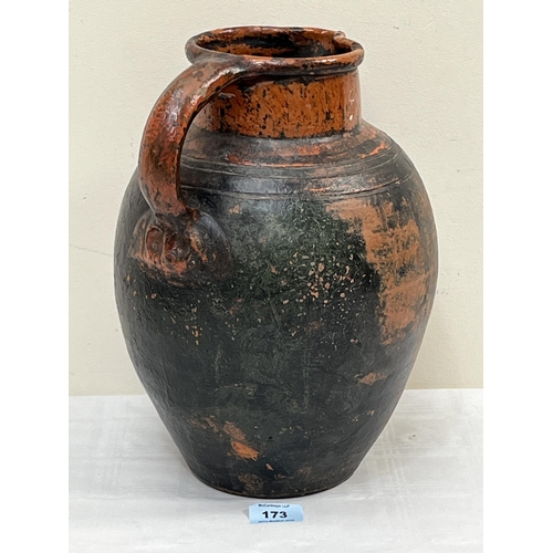 173 - An antique glazed terracotta earthenware jug decorated in red slip with a dragon. 12½