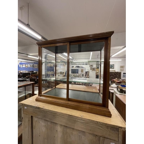 37 - Early 20th cent. Display case, sliding glass doors to the back, two glass shelves on a moulded base.... 