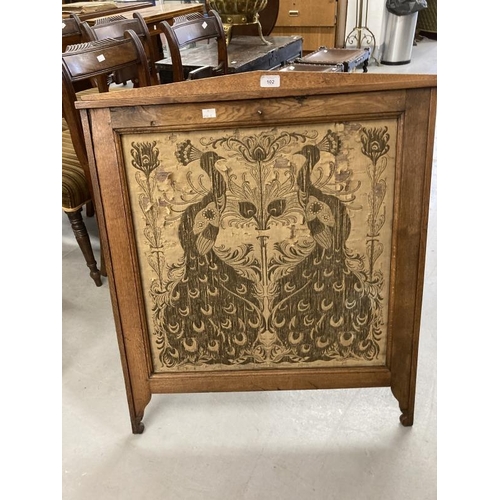 102 - Arts & Crafts: Oak fire screen with inset tapestry panel depicting peacocks.