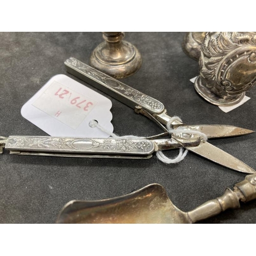 403 - White metal and steel folding scissors the handles with relief decoration of flowers and a central c... 