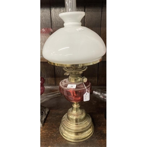 10 - Victorian oil lamp brass base, cranberry glass reservoir, white shade marked Hinks's Duplex. 23½ins.