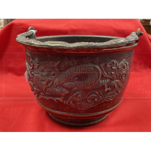 409 - Early 20th cent. Chinese bronze rice pot depicting a dragon on both sides and a shaped handle. 6ins.... 