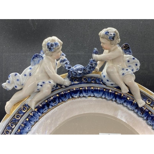 453 - 19th cent. Porcelain oval framed mirror, bevelled glass, decorated with cherubs and flowers. Approx.... 