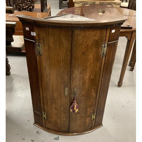 76 - 18th cent. Oak bow front hanging corner cupboard dentil cornice above 2 doors on a moulded base, the... 