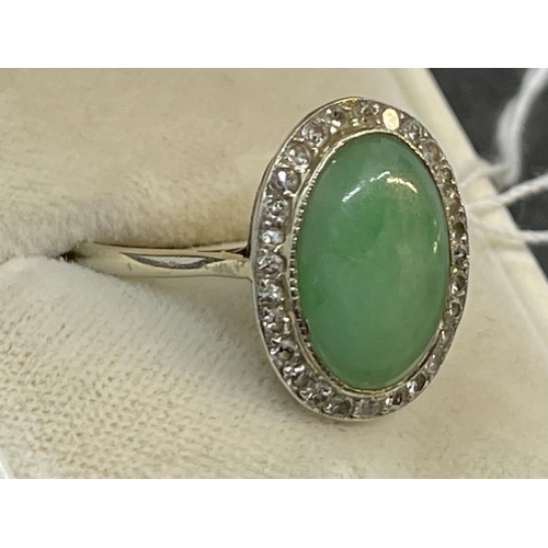 658 - Hallmarked Jewellery: White metal ring set with a 14mm x 10mm cabochon cut jade surrounded by thirty... 