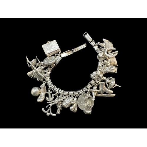 730 - Jewellery: White metal bracelet marked silver and tests as such, with 25 charms. Gross weight 62g.... 