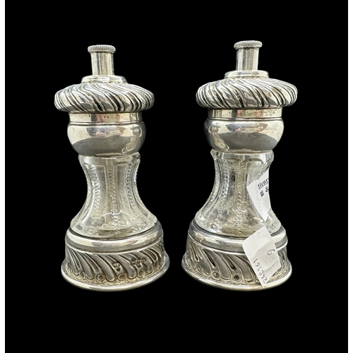 718 - Silver: Waisted cut glass pepper grinders mounted with writhen decorated silver, London 1899, a pair... 