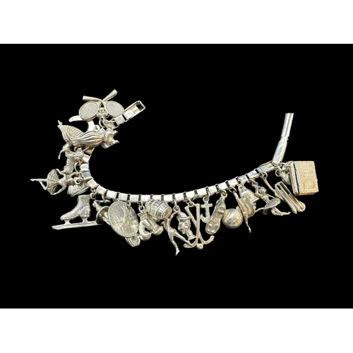 730 - Jewellery: White metal bracelet marked silver and tests as such, with 25 charms. Gross weight 62g.... 