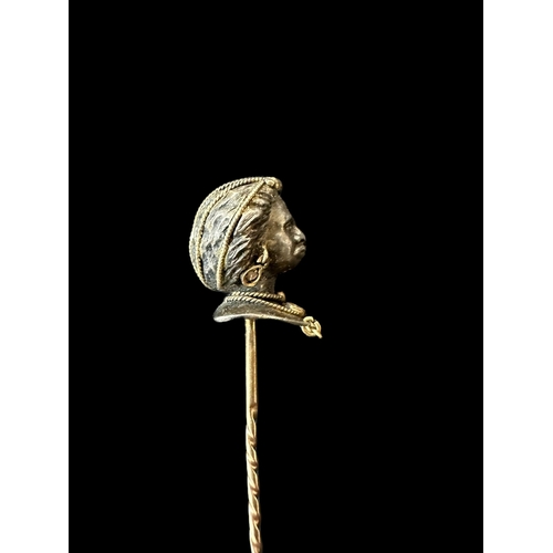 806 - Jewellery: Yellow and white metal stick pin modelled as a blackamoor wearing diamond earrings and ne... 