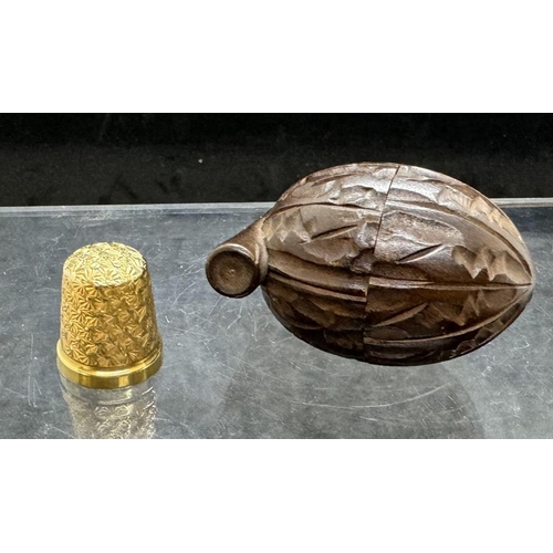 731 - Objects of Vertu: A 9ct gold thimble, Chester 1930, 5.4g, with Black Forest holder carved as a nut.... 