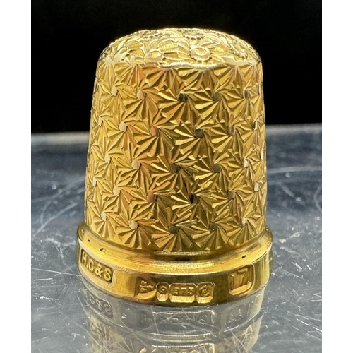 731 - Objects of Vertu: A 9ct gold thimble, Chester 1930, 5.4g, with Black Forest holder carved as a nut.... 