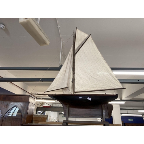 98 - Toys & Games: Treen racing pond yacht fully rigged, red hull, racing keel, on stand. 128cm x 118... 