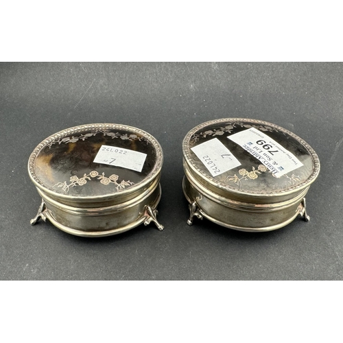 799 - Silver: Pair of circular tortoiseshell lids inlaid with silver pique work with a raised border, both... 