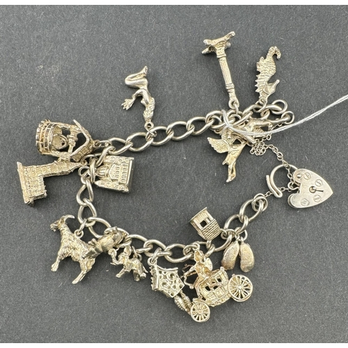 839 - Jewellery: A silver curb link bracelet with heart clasp, hung with in excess of fifteen charms inclu... 